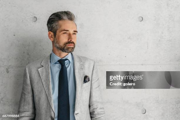 handsome bearded businessman standing in front of concrete wall - 40 year old male models stock pictures, royalty-free photos & images