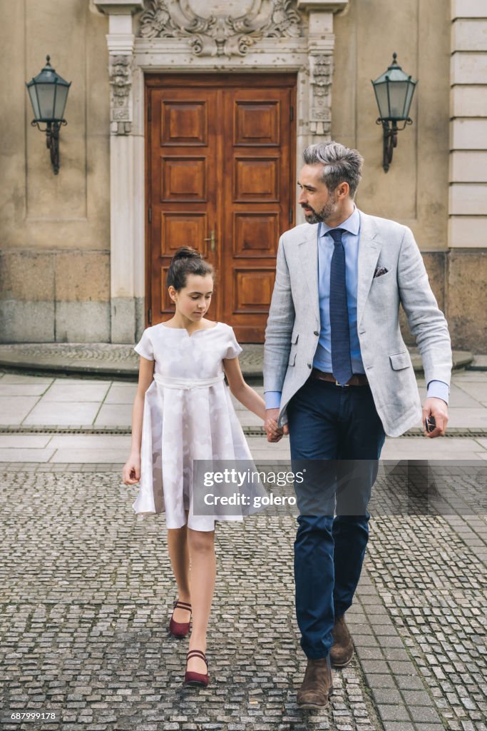 Elegante Vater hand in hand gehen mit festlich gekleidet Teenager-Tochter