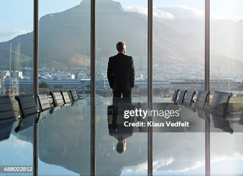 Portrait of male CEO in big corner office, looking out of window Portrait of male CEO in big corner office, looking out of window