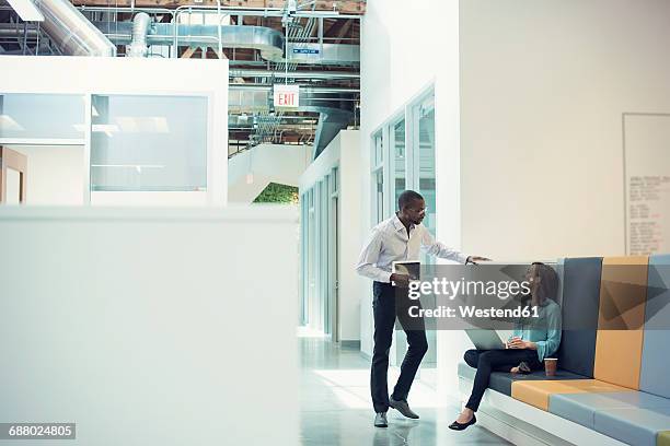 colleagues talking in corridor, using mobile devices - office hallway stock pictures, royalty-free photos & images