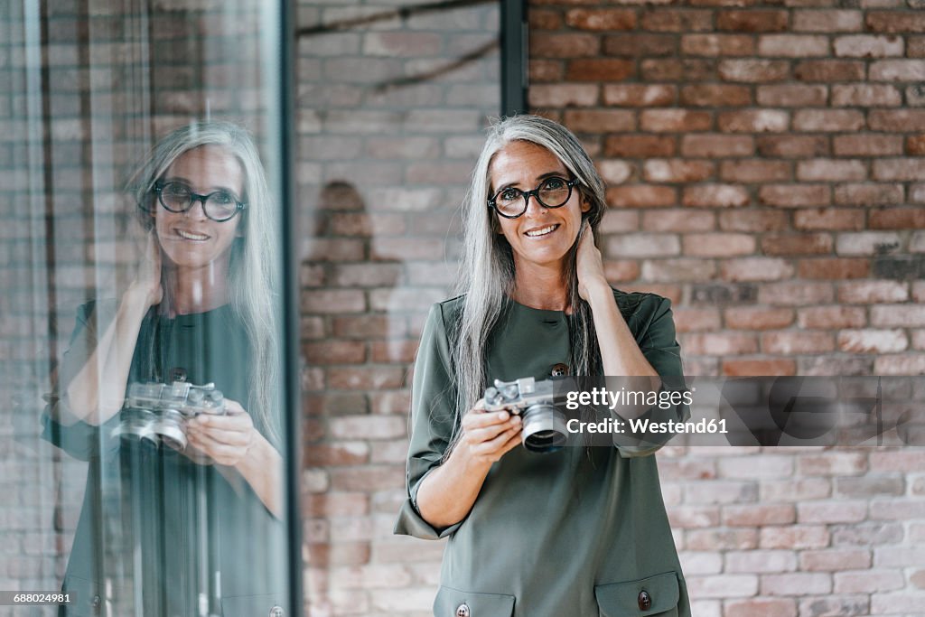 Portrait of smiling woman with long grey hair holding camera