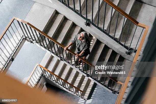 woman with long grey hair in staircase - hinauf bewegen stock-fotos und bilder
