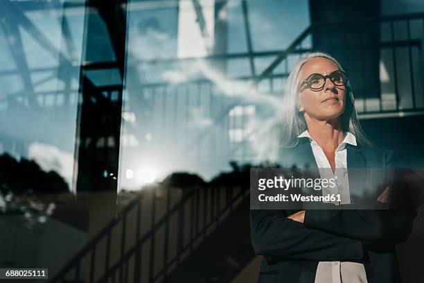 businesswoman looking out of window - reflection stock-fotos und bilder