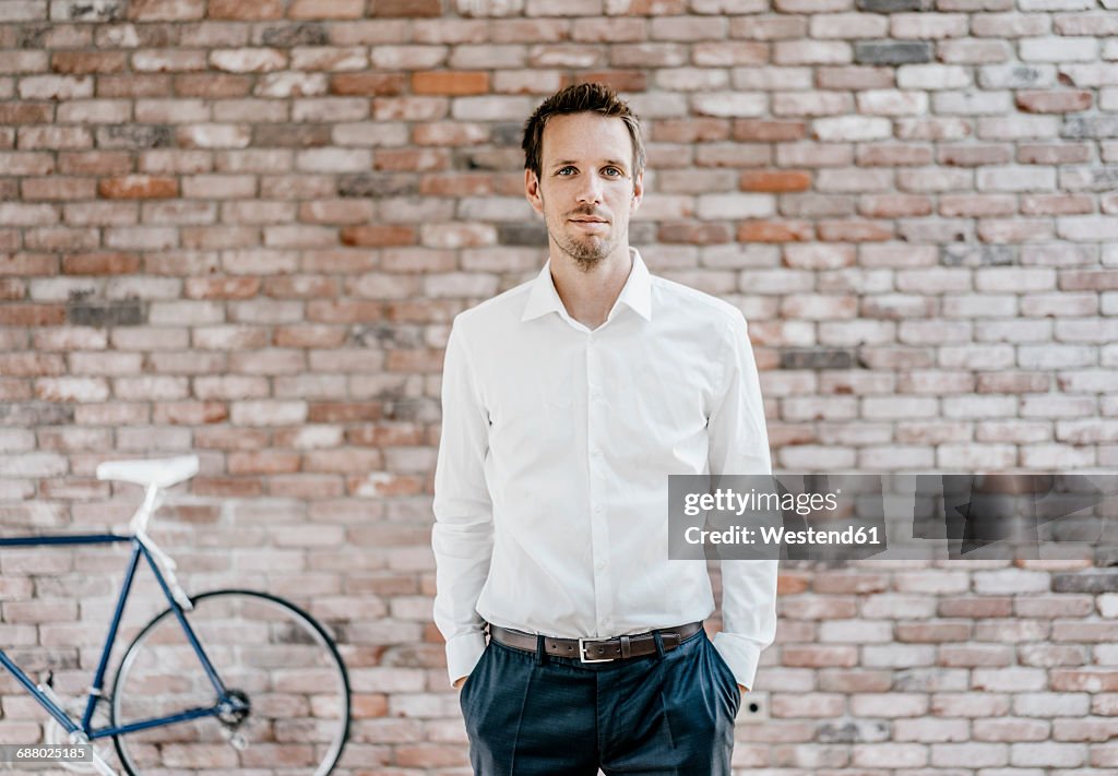 Portrait of confident businessman in front of brick wall