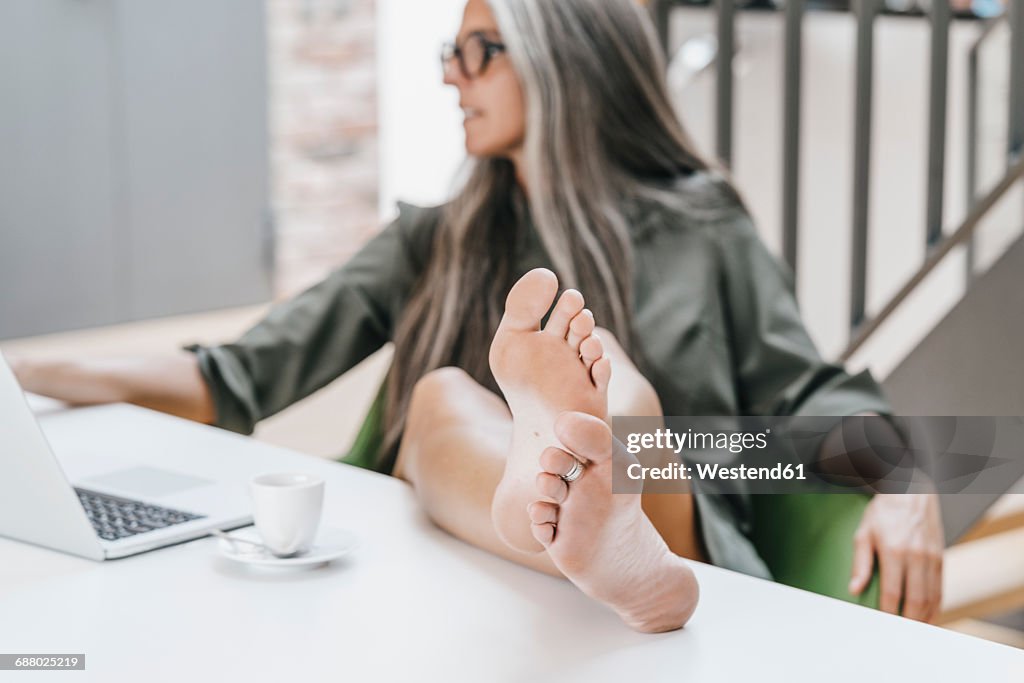 Woman Working In Office With Bare Feet On Desk High-Res Stock