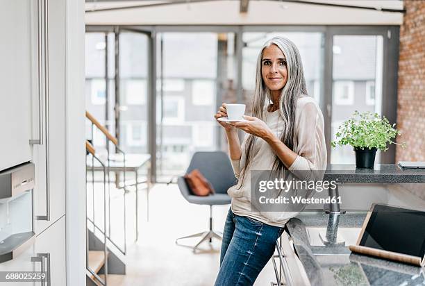 smiling woman with long grey hair drinking coffee - gray hair fotografías e imágenes de stock