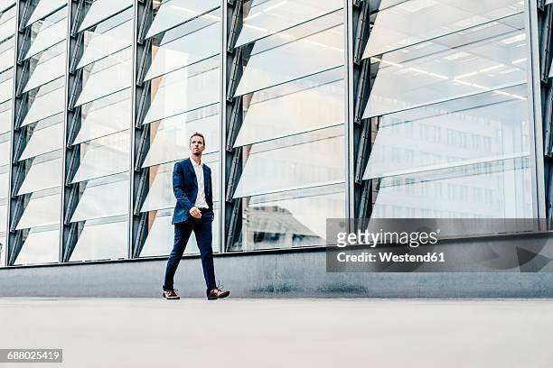 germany, berlin, businessman walking at potsdamer platz - business man modern city photos et images de collection