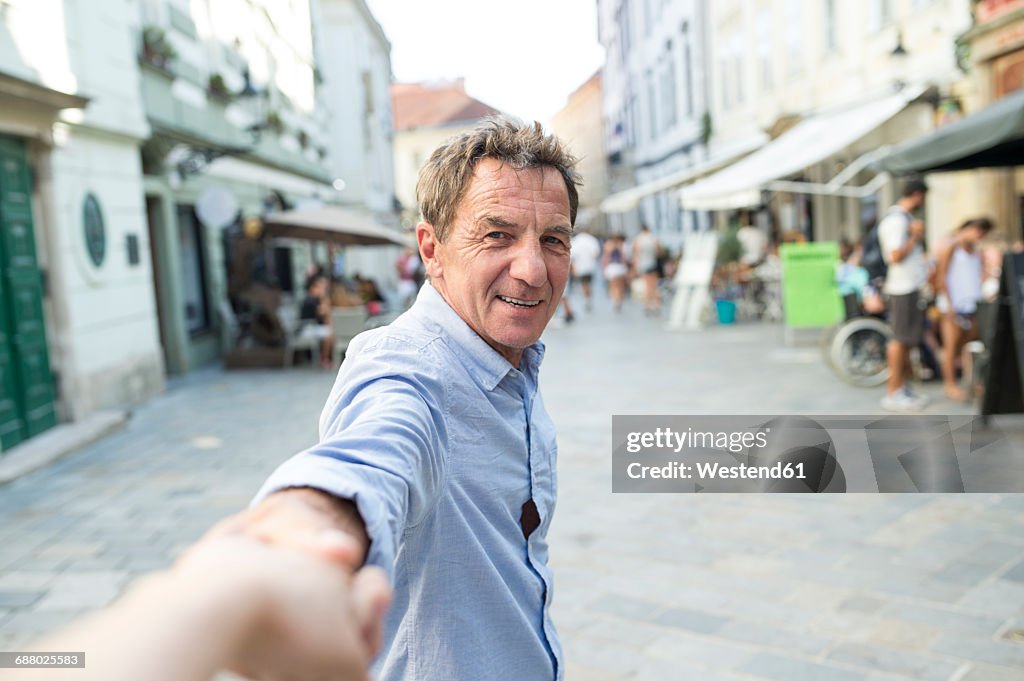 Slovakia, Bratislava, portrait of happy senior man holding hand on the street