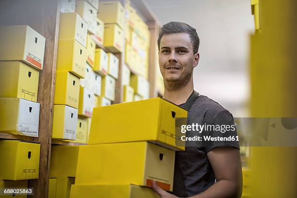 man in warehouse carrying shoe boxes - schoenendoos stockfoto's en -beelden