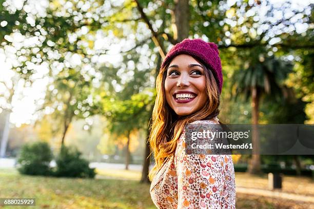 happy young woman wearing wooly hat in a park in autumn - chapéu roxo imagens e fotografias de stock