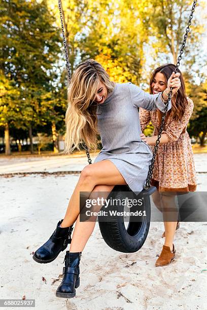 two playful young women on a tire swing - tyre swing stock pictures, royalty-free photos & images