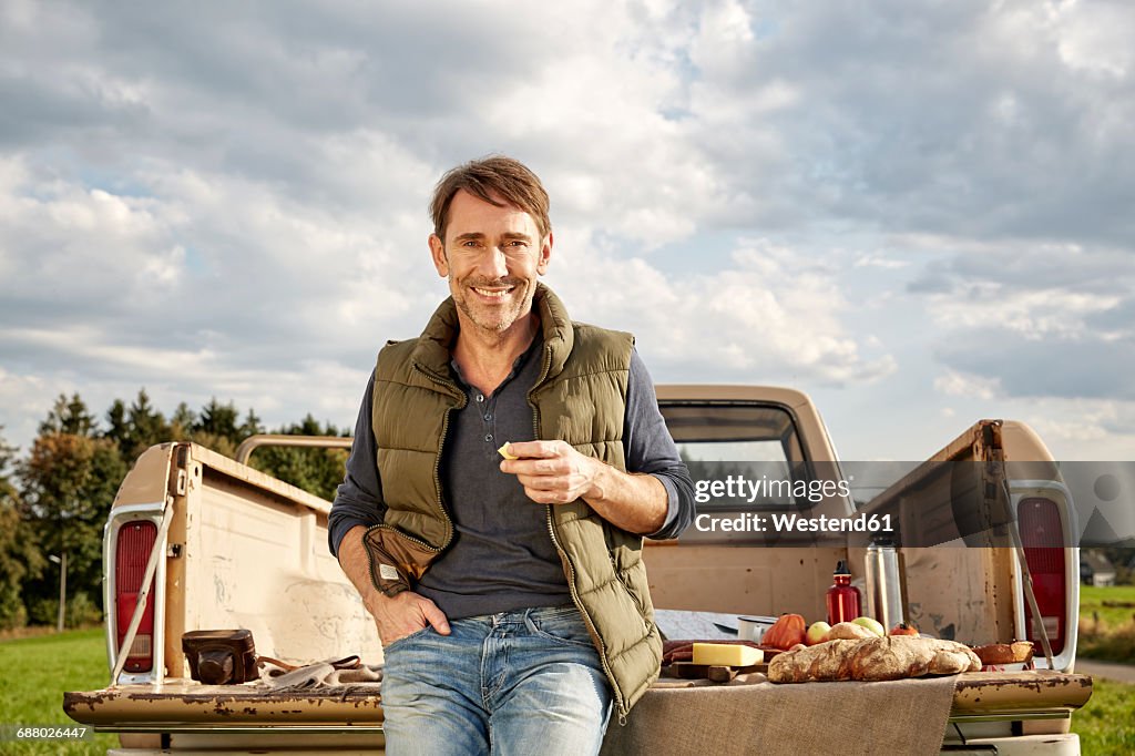 Portrait of smiling man at pick up truck having picnic