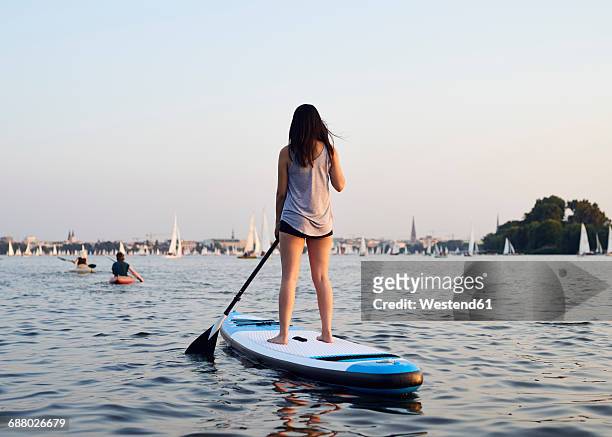 germany, hamburg, young woman on paddleboard enjoying summer - hamburg stock-fotos und bilder