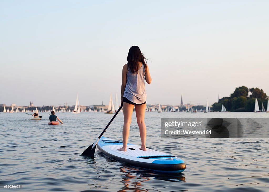 Germany, Hamburg, Young woman on paddleboard enjoying summer