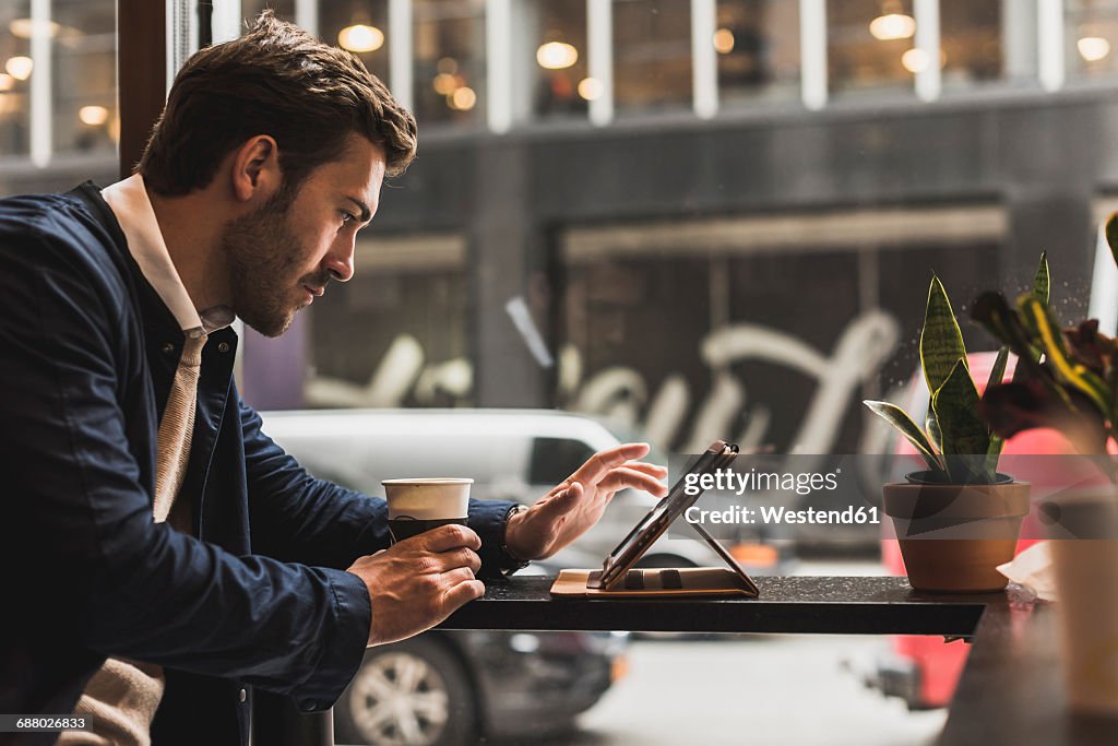 USA, New York City, Businessman sitting in coffee shop, using digital tablet