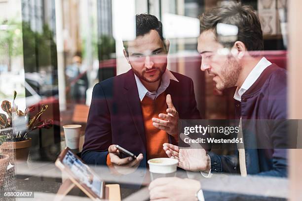 usa, new york city, businessmen meeting in coffee shop, using mobile devices - two executive man coffee shop stock pictures, royalty-free photos & images