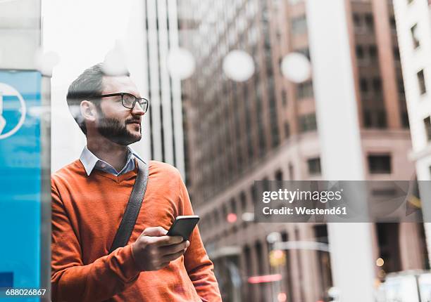 usa, new york city, businessman leaning on atm holding smart phone - beard men street foto e immagini stock