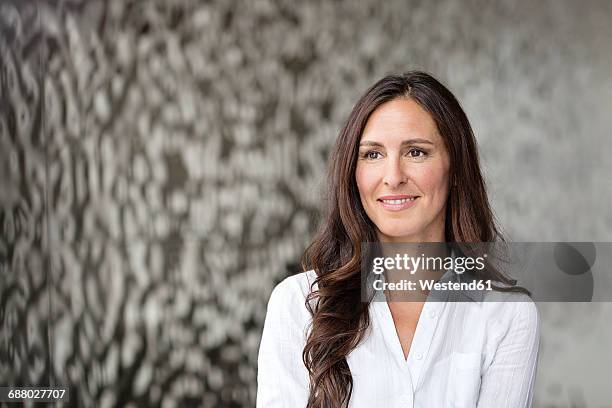 portrait of confident businesswoman in front of rippled wall - brown hair stock-fotos und bilder