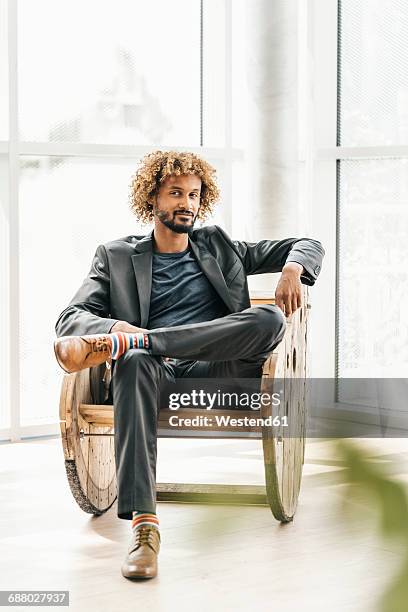 young businessman sitting in wooden rocking chair - schaukelstuhl stock-fotos und bilder