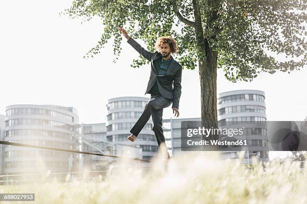 young businessman balancing on slackline - rope walking stock pictures, royalty-free photos & images