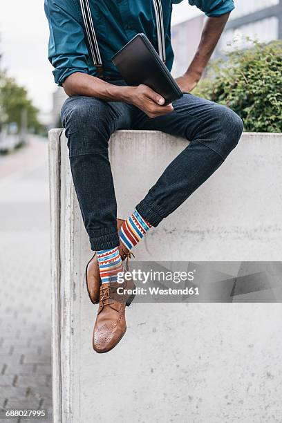 young man sitting on wall, holding laptop - cool man leather stock pictures, royalty-free photos & images