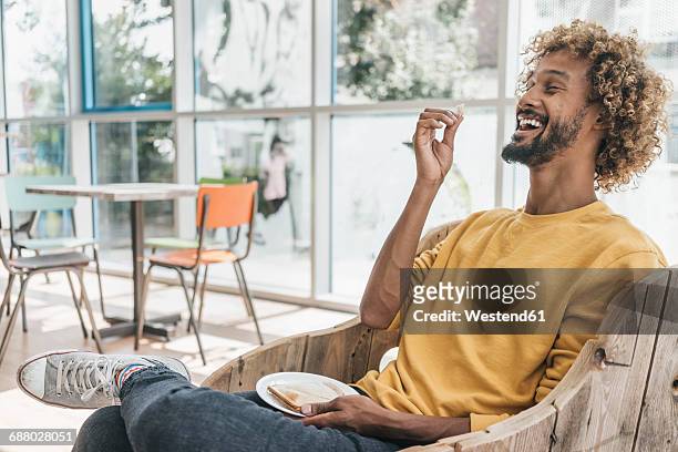 laughing young man eating sandwich - indulgence photos et images de collection