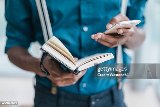 young man using smart phone, holding note book - address book stock pictures, royalty-free photos & images