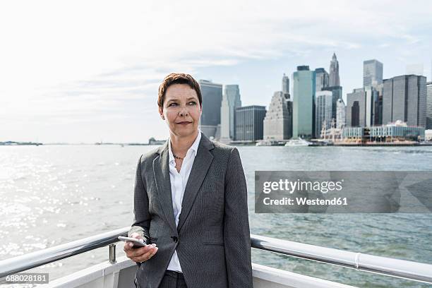usa, brooklyn, portrait of pensive businesswoman standing on boat - businesswoman nyc stock pictures, royalty-free photos & images