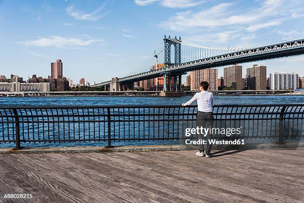 usa, brooklyn, back view of businesswoman looking at east river - manhattan bridge stock pictures, royalty-free photos & images