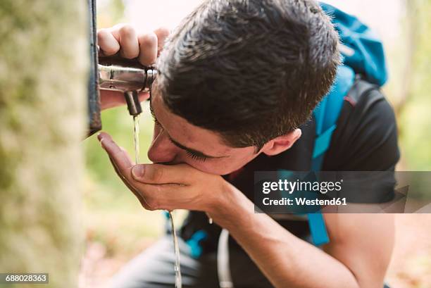 hiker drinking water from a well - galizien stock-fotos und bilder