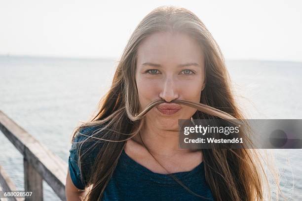 portrait of young woman pulling funny face - frau haarsträhne blond beauty stock-fotos und bilder