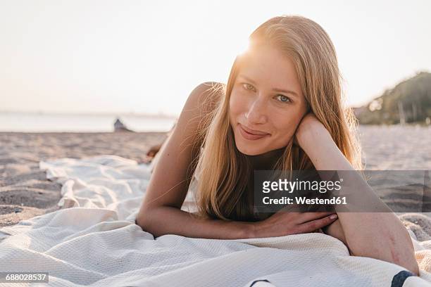 portrait of young woman lying on blanket on the beach - de bruços imagens e fotografias de stock