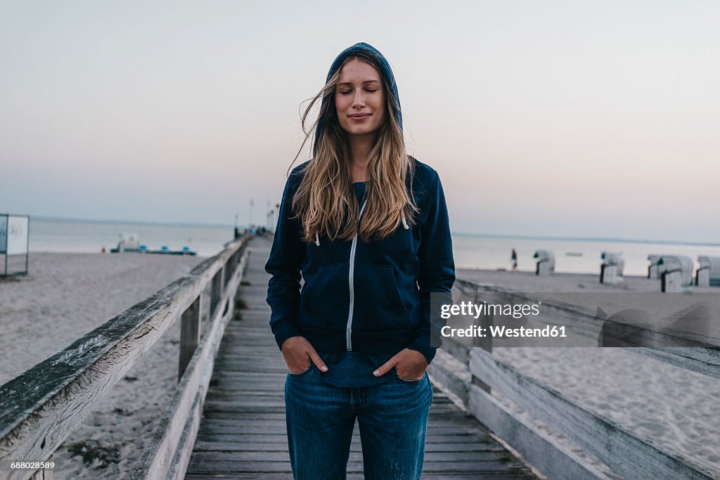Portrait of smiling young woman with eyes closed standing on jetty