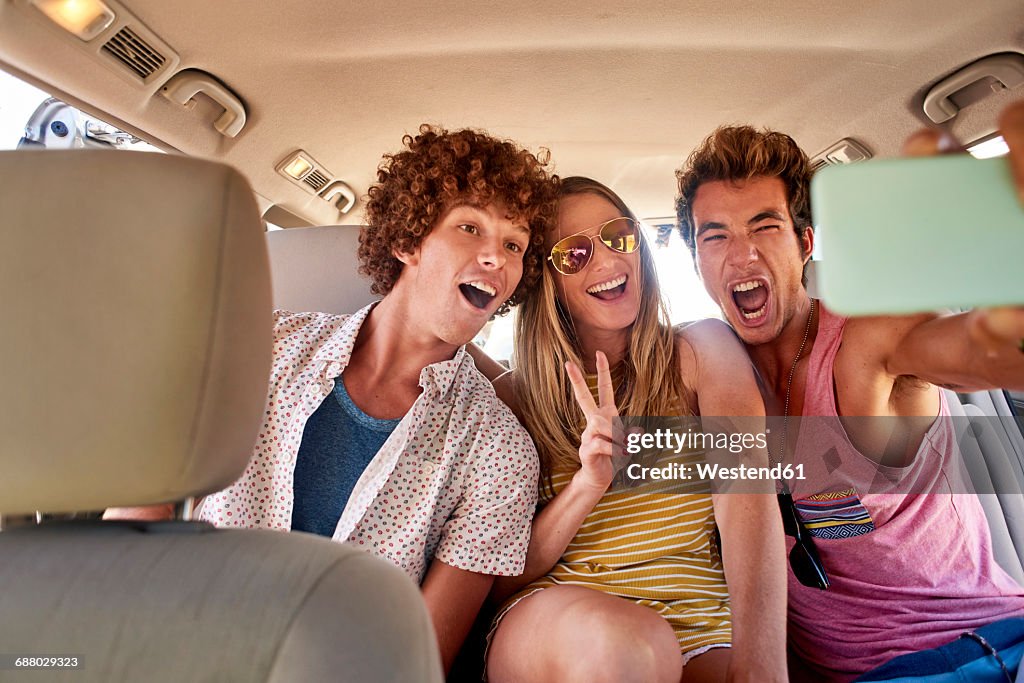Happy friends in a car taking a selfie
