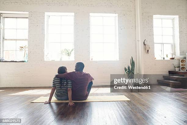 young couple sitting on carpet in a loft - einzug gegenlicht stock-fotos und bilder