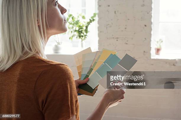 young woman in a loft thinking about color samples - a woman with paint stock-fotos und bilder