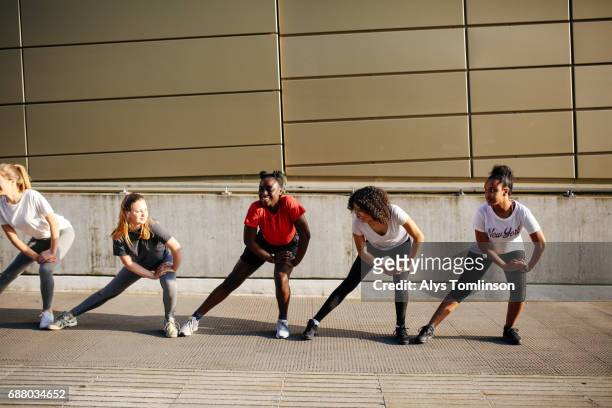 group of young women in urban setting, stretching during fitness warm-up - girls in leggings stock-fotos und bilder
