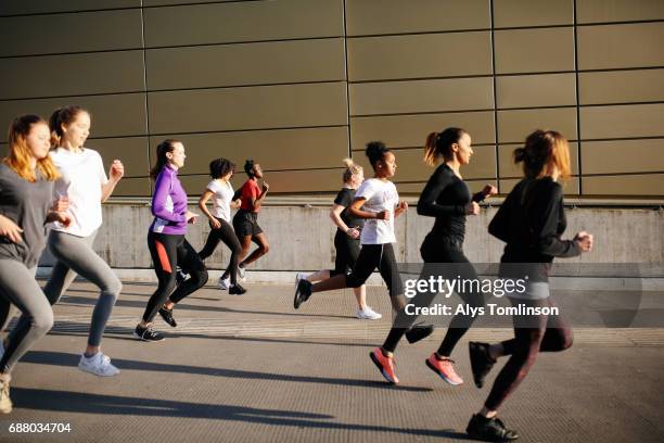 group of young women running in city setting - center athlete stock-fotos und bilder