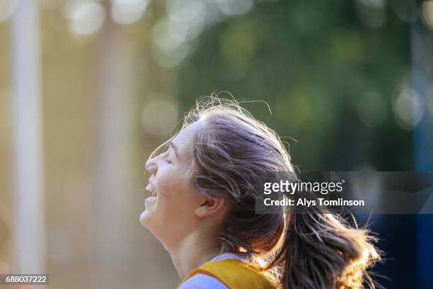 close-up profile shot of young, female netball player laughing on court - girl laughing stock pictures, royalty-free photos & images
