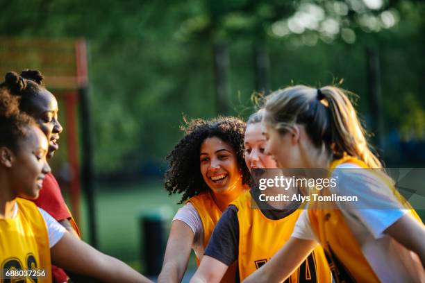 group of young netball players with hands together, before start of match on outdoor court - talent team coaching stock-fotos und bilder