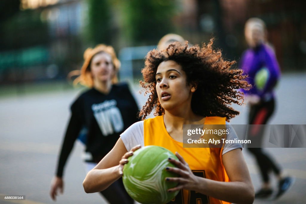 Action shot of netball player catching ball on outdoor sports court