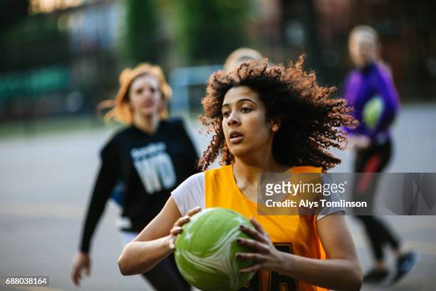 action shot of netball player catching ball on outdoor sports court - netball team stockfoto's en -beelden