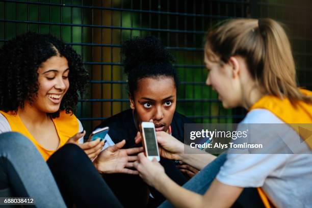 netball team looking at their phones on sidelines of outdoor court - prop sporting position stock pictures, royalty-free photos & images