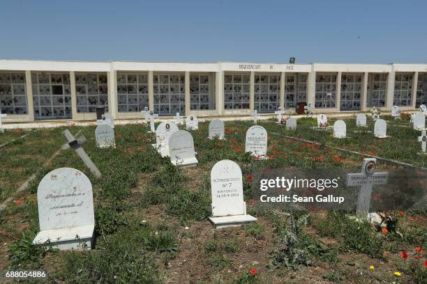Tombstones stand at graves that, according to the cemetery caretaker, are the graves of migrants who died while trying to reach Italy on the island...
