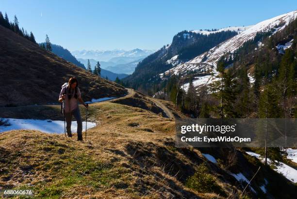 Female hiker is walking a trail up to the mountain hut Priener Huette with a panoramic view on Wilder Kaiser in Austria on March 26, 2017 in...