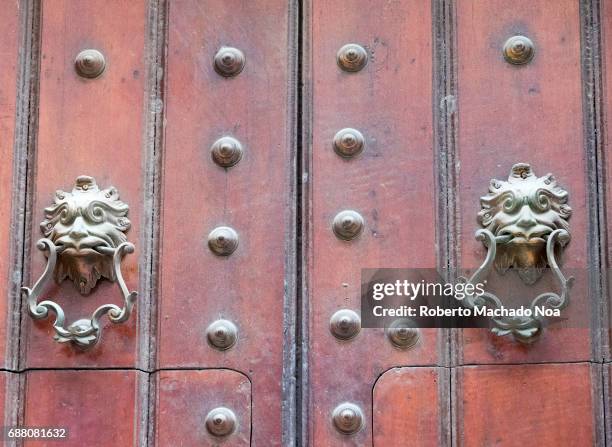 Architecture detail in Unesco World Heritage Site: Close-up of an ornate wooden door adorned with metal buttons and lion door knockers.