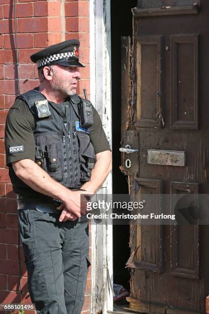 Policeman stands guard next to a home in Moss Side where explosive damage can be seen after being raided by anti-terror police during the...