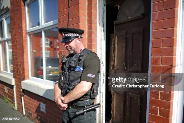 Policeman stands guard next to a home in Moss Side where explosive damage can be seen after being raided by anti-terror police during the...