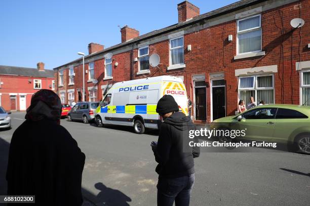 Local residents stand in the street next to a home in Mosside where explosive damage can be seen after the property was raided by anti-terror police...