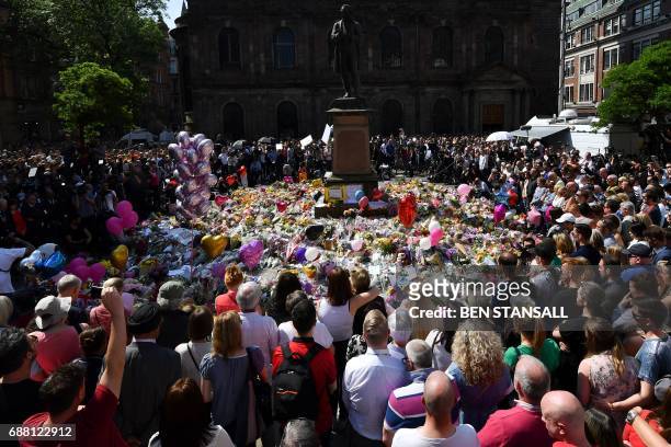People stop to observe a minute's silence in St Ann's Square gathered around the tributes, in central Manchester, northwest England, on May 25 as a...